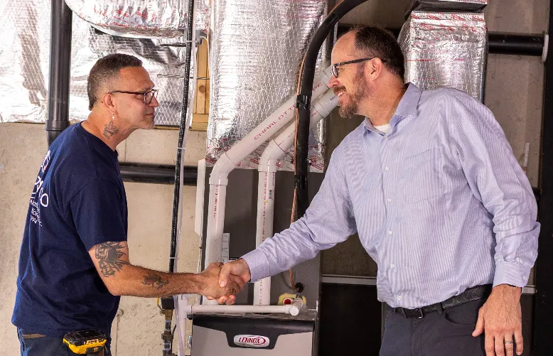 A technician and a customer shakings hands and smiling